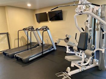 a room with two treadmills and televisions